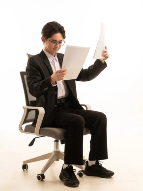 اعداد تقرير خاص بالعمل، بورتريه لرجل اسيوى يرتدى البدلة الرسمية يجلس على كرسي مريح ينظر إلى أوراق بيضاء، إيماءات التركيز والاندماج، خلفية بيضاء