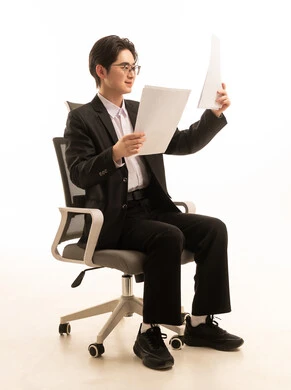 قراءة الملاحظات والمعلومات، بورترية لرجل اسيوى يرتدي البدلة الرسمية يحمل بيديه ورقة بيضاء يجلس على كرسى، متابعة الخطط والمشاريع، خلفية بيضاء