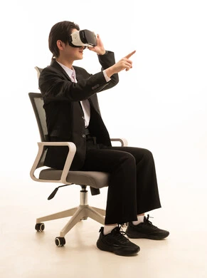 الاندماج ومحاكاة العالم الخيالي، التطور التقني والتكنولوجي، المتعة و التسلية بالمشاهدة عبر نظارة الواقع الافتراضي، بورتريه لشاب اسيوى يرتدى البدلة الرسمية يجلس على الكرسي ينظر من خلال نظارات ثلاثية الأبعاد, خلفية بيضاء