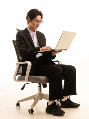 Fast and secure online shopping, using a modern advanced technical device, a portrait of an Asian man in a formal suit sitting on a chair holding a computer browsing the internet, remote work, white background.