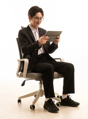 استخدام جهاز تقني حديث متطور، بورتريه لرجل اسيوى يرتدي البدلة الرسمية يجلس على كرسى يحمل التابلت يتصفح الانترنت, العمل عن بعد،, التسوق الإلكتروني السريع والآمن، خلفية بيضاء