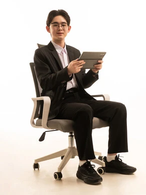 بورتريه لرجل اسيوى يرتدي البدلة الرسمية يجلس على كرسى يحمل التابلت يتصفح الانترنت, العمل عن بعد، التسوق الإلكتروني السريع والآمن، خلفية بيضاء