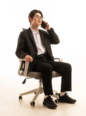 اجراء مكالمة هاتفية، بورتريه لرجل اسيوى يرتدى البدلة الرسمية يجلس على كرسي مريح يمسك الهاتف المحمول بتعابير السعادة, استخدام جهاز تقنى حديث، إرسال الرسائل النصية والصوتية عبر الجوال، خلفية بيضاء