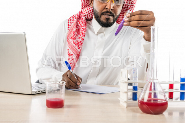 بورتريه لرجل خليجي سعودي ، بالزي السعودي التقليدي ، يقوم بتسجيل الملاحظات ، إستخدام جهاز الحاسوب المحمول، إستخدام انابيب الاختبار لإجراء التجارب، إجراء تجارب وتفاعلات كيميائية في المختبر، تجارب وأبحاث علمية، دراسات وتحاليل، مختبر ومعمل الكيمياء، خلفية بيض