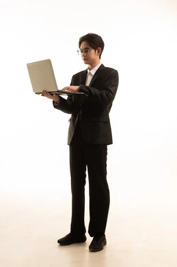التسوق الإلكتروني السريع والآمن، إستخدام جهاز تقنى حديث، بورتريه لرجل اسيوى يرتدي البدلة الرسمية يحمل اللاب توب ينطر الى الكاميرا,  العمل عن بعد، صورة للجسم بالطول الكامل, خلفية بيضاء