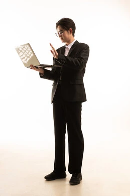 إجراء مكالمة فيديو بإستخدام جهاز الحاسوب المحمول، بورتريه لرجل اسيوى يرتدي البدلة الرسمية يحمل اللاب توب, التسوق الإلكتروني السريع والآمن، العمل عن بعد، صورة للجسم بالطول الكامل, خلفية بيضاء