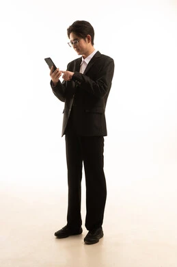 Following social media via mobile phone, using advanced technical devices, a portrait of an Asian man in a formal suit using a mobile phone, a full-body image, white background.