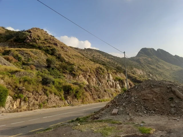 منظر طبيعي متميز للجبل في منطقة الباحة في المملكة العربية السعودية، الاهتمام بزراعة أشجار النخيل الخضراء في قرية الرخام في ذي عين الأثرية, التكوين والتشكيل الصخري للمرتفع الجبلي, معلم سياحي مشهور، مكان جذب واستقطاب السائحين