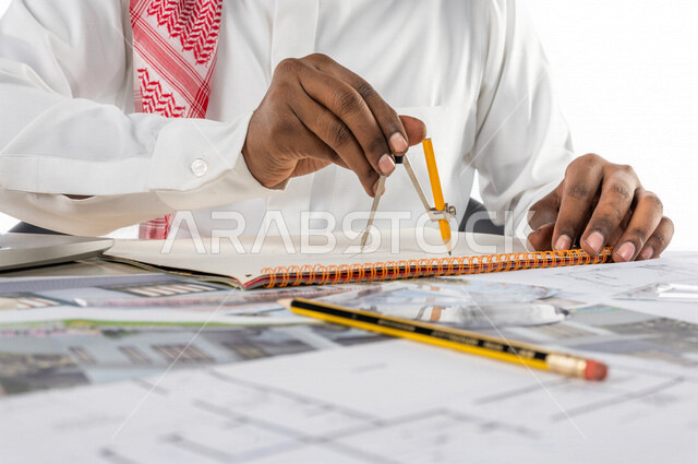 بورتريه  لمهندس خليجي سعودي داخل مكتب هندسي ، إستخدام جهاز الحاسوب المحمول للإنجاز وتتبع المهام ، خوذة الوقاية ، استخدام أدوات ومعدات هندسية  على مخطط تصميم هندسي ، مهن ووظائف هندسية ، خلفية بيضاء ، مفهوم الهندسة المعمارية ، مهندس معماري محترف