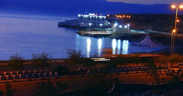 انعكاس الاضاءة الملونة على مياه البحر، ساحل البحر الاحمر في تبوك شمال المملكة العربية السعودية ، كورنيش ساحل خليج العقبة المضاء في وقت الليل، مناطق سياحية لقضاء وقت ممتع