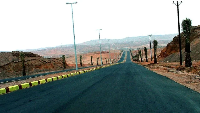 Facilitating movement between rural areas and cities, the development and urban growth in the deserts of the Kingdom, a paved street for vehicle passage and speeding up the movement of travelers in Tabuk, an asphalt road extending along the desert, the formation of dunes and sandy hills, the dry desert environment in Saudi Arabia.