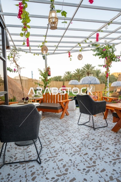 منطقة جلوس خارجية في مقهى بقرية عقدة، طابع ريفي وسط الجبال وأشجار النخيل، نسيم الجبال البارد، تجربة تجمع بين الراحة والهدوء والطبيعة في أحد مواقع ومعالم السياحة فى مدينة حائل بالمملكة العربية السعودية