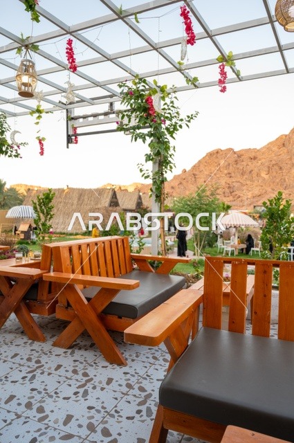 منطقة جلوس خارجية في مقهى بقرية عقدة، طابع ريفي وسط الجبال وأشجار النخيل، نسيم الجبال البارد، تجربة تجمع بين الراحة والهدوء والطبيعة في أحد مواقع ومعالم السياحة فى مدينة حائل بالمملكة العربية السعودية