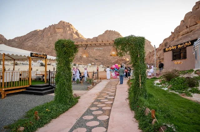 An outdoor seating area in a café in the village of Aqda, with a rustic character amidst the mountains and palm trees, a cool mountain breeze, an experience that combines comfort, tranquility, and nature in one of the tourist sites and landmarks in the city of Hail, Saudi Arabia. An outdoor seating area in a café in the village of Aqda, with a rustic character amidst the mountains and palm trees, a cool mountain breeze, an experience that combines comfort, tranquility, and nature in one of the tourist sites and landmarks in the city of Hail, Saudi Arabia.
