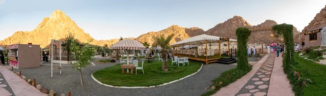 An outdoor seating area in a café in the village of Aqda, with a rustic character amidst the mountains and palm trees, a cool mountain breeze, an experience that combines comfort, tranquility, and nature in one of the tourist sites and landmarks in the city of Hail, Saudi Arabia.