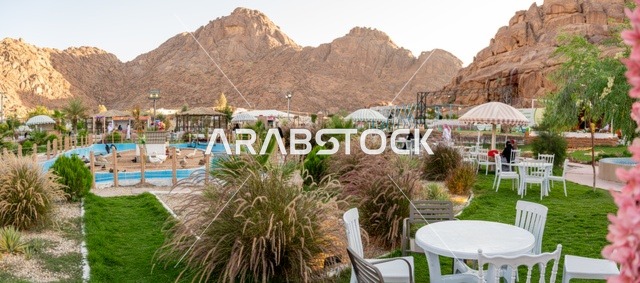 تجربة تجمع بين الراحة والهدوء والطبيعة في أحد مواقع ومعالم السياحة فى مدينة حائل بالمملكة العربية السعودية، منطقة جلوس خارجية في مقهى بقرية عقدة، طابع ريفي وسط الجبال وأشجار النخيل، نسيم الجبال البارد