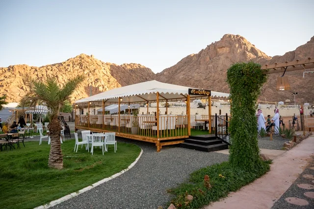 تجربة تجمع بين الراحة والهدوء والطبيعة في أحد مواقع ومعالم السياحة فى مدينة حائل بالمملكة العربية السعودية، منطقة جلوس خارجية في مقهى بقرية عقدة، طابع ريفي وسط الجبال وأشجار النخيل، نسيم الجبال البارد