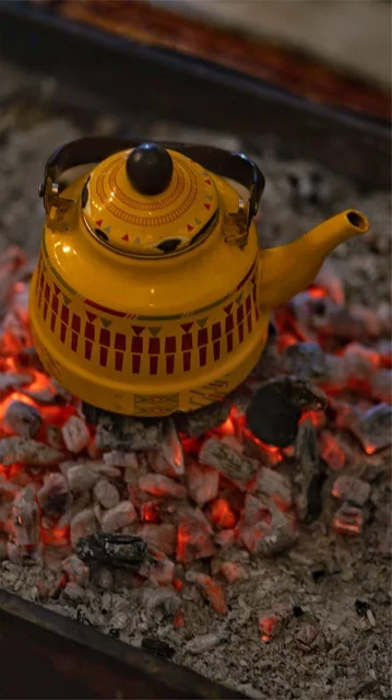 A picture of a teapot on burning firewood, outdoor trips, winter atmosphere, a popular Arab gathering, a teapot on the firewood, a campfire.