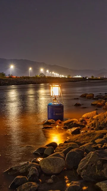 A glowing metal lamp on the beach sand, the beach, the calm of the sea, landscapes.