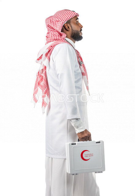 بورتريه بمنظر جانبي لرجل عربي خليجي سعودي ، يرتدي المعطف الطبي الخاص بمهنة الطبيب ، يحمل بيده حقيبة الإسعافات الأولية ، يقوم بالسير بمفهوم لغة الجسد المختلفة ، مفهوم الطب ، خلفية بيضاء ، مهن و وظائف طبية ، مفهوم الخدمات الطبية الطارئة ، طوارئ طبية