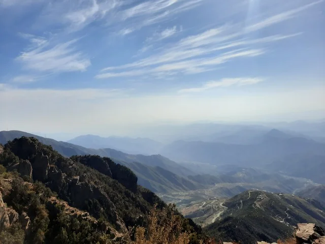 An aerial image of the mountainous environment, plateaus, and highlands, a view of the sky above the landscapes in Al-Soudah Park, the grasses, trees, and green plants in the Soudah Mountains in the Asir region, famous natural tourist spots and areas in the Kingdom of Saudi Arabia.
