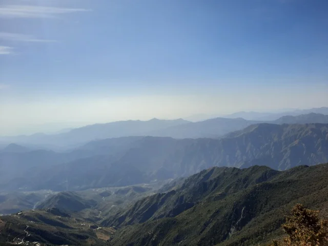 The herbs, trees, and green plants in the Asir region's Soudah Mountains, an aerial image of the mountainous environment, plateaus, and highlands, a view of the sky above the natural landscapes in Soudah Park, famous natural tourist spots and areas in the Kingdom of Saudi Arabia.
