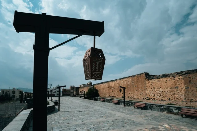 الفوانيس الخشبيه وأعمده الإنارة المتميزة حول القلعة الاثريه التاريخيه في منطقة عسير, الأماكن والمعالم السياحية المشهورة في مدينه أبها, البناء المشيد من الأحجار وجذوع أشجار العرعر, التصميم المعماري القديم للقلاع الحصينيه العسكرية في قرية شمسان