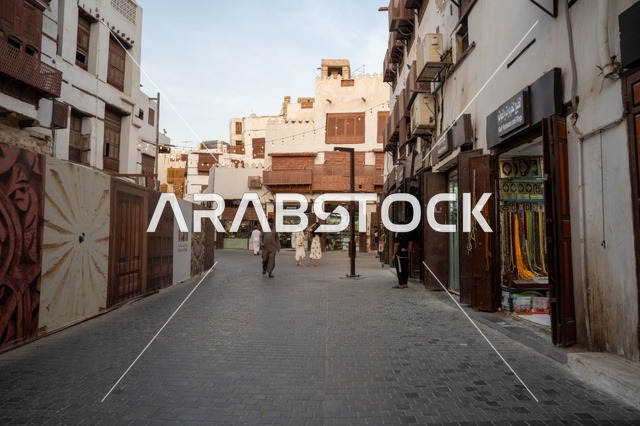 تجول المواطنين في الأحياء القديمة، المعالم التاريخية في جدة، المحلات التجارية في حواري البلد التاريخي في مدينة جدة في المملكة العربية السعودية ، التصميم المعماري العربي القديم للمباني الأثرية