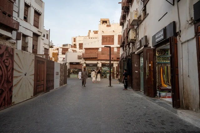 تجول المواطنين في الأحياء القديمة، المعالم التاريخية في جدة، المحلات التجارية في حواري البلد التاريخي في مدينة جدة في المملكة العربية السعودية ، التصميم المعماري العربي القديم للمباني الأثرية