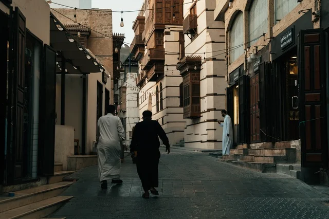 تجول المواطنين في الأحياء القديمة، المعالم التاريخية في جدة، المحلات التجارية في حواري البلد التاريخي في مدينة جدة في المملكة العربية السعودية ، التصميم المعماري العربي القديم للمباني الأثرية