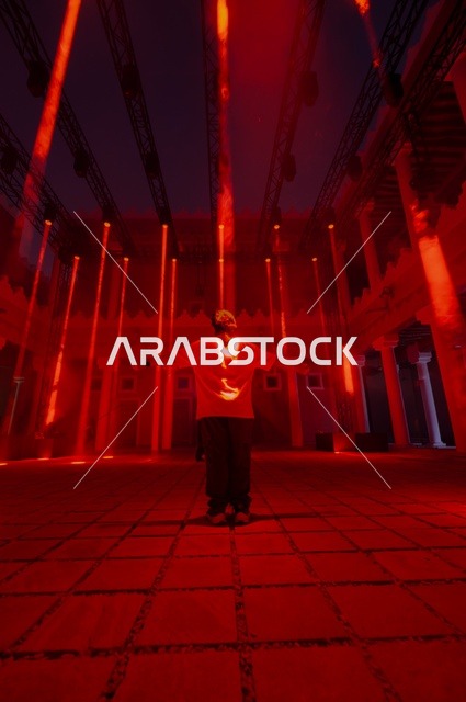 مهرجان نور الرياض السعوديه ، رجل عربي خليجي سعودي يرتدي الزي الكاجوال  يقف بتعابير السعادة، الاستمتاع باشكال فنون الضوء ،فعاليات و انشطة ترفيهيه ممتعه لجذب السياح من الخارج ،احتفالات ومناسبات سنويه ،عروض الاضاءه الملونه  ،رحله فنيه للتحول الضوئي الإبداعي