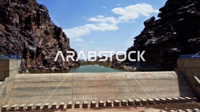 The structure of the Al-Musayriq Valley Dam in southern Khyber, Asir region, the harsh mountainous nature, a water storage area, peaks and highlands and terrain, historical archaeological landmarks in the Kingdom of Saudi Arabia, natural background.