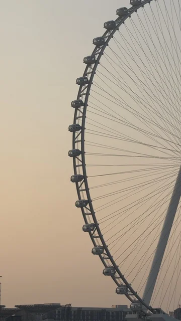 Progress, growth, and urban expansion, a picture of the Dubai Eye wheel among the buildings, the architectural engineering art of the facilities, Dubai's tourist landmarks, towers, and skyscrapers in the United Arab Emirates.
