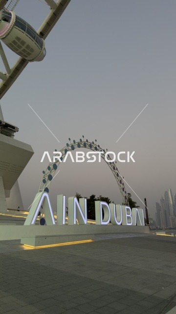 A picture of the Dubai Eye wheel among the buildings, progress, growth, and urban expansion, the architectural engineering art of the facilities, Dubai's tourist landmarks, towers, and skyscrapers in the United Arab Emirates.