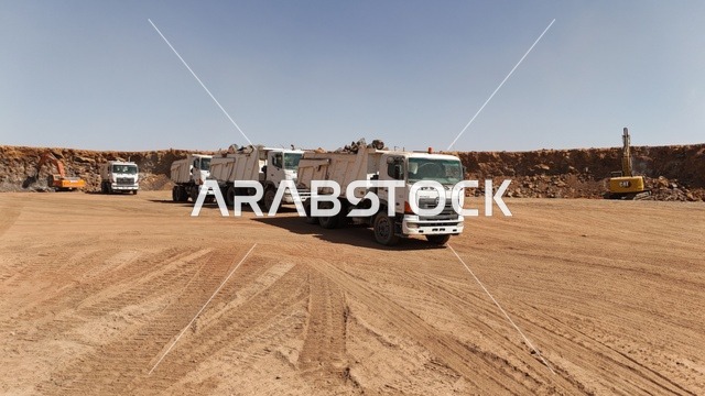 An industrial engineering profession and job in Saudi Arabia, massive excavators working in digging and lifting debris and soil at the work site, reliance on heavy machinery and equipment in construction work, the concept of architecture and construction, improving infrastructure for the establishment of modern buildings and projects in the city of Riyadh.