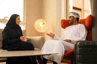 Drinking Arabic coffee, spending enjoyable family time, understanding and intellectual bonding between spouses, sitting in a luxury hotel, an Arab Gulf Omani man wearing a dishdasha and kumma sitting next to a suitcase exchanging conversations with his wife, gestures of happiness and joy. Drinking Arabic coffee, spending enjoyable family time, understanding and intellectual bonding between spouses, sitting in a luxury hotel, an Arab Gulf Omani man wearing a dishdasha and kumma sitting next to a suitcase exchanging conversations with his wife, gestures of happiness and joy.