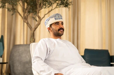 النظر الى شيء ما , رجل عربي خليجي عماني يرتدي الدشداشة و العمامة يجلس في لوبي الفندق ، مفهوم الاهتمام بالمظهر الخارجي والشياكة