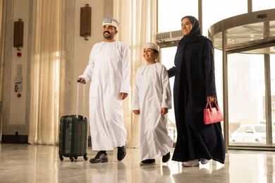 عطلة نهاية الأسبوع ، رحلة عائلية ترفيهية، ايماءات السعادة و الحماس، رجل عربي خليجي عماني يرتدي الدشداشة و العمامة يمسك بيديه حقيبة السفر يمشي داخل بهو الفندق برفقة زوجته و ابنه ، قضاء أجمل الأوقات في أفضل الفنادق الخليجية، أجواء عائلية مرحة عطلة نهاية الأسبوع ، رحلة عائلية ترفيهية، ايماءات السعادة و الحماس، رجل عربي خليجي عماني يرتدي الدشداشة و العمامة يمسك بيديه حقيبة السفر يمشي داخل بهو الفندق برفقة زوجته و ابنه ، قضاء أجمل الأوقات في أفضل الفنادق الخليجية، أجواء عائلية مرحة