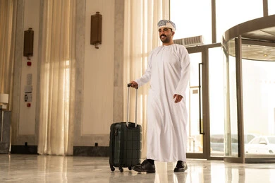 مفهوم السياحة في إجازة الصيف، الاستعداد للسفر في جولة سياحية، رجل عربي عماني خليجي يرتدي الدشداشة و العمامة يقوم بجر حقيبة الامتعة في بهو الفندق، تعابير وايماءات السعادة والسرور، قضاء وقت ممتع مفهوم السياحة في إجازة الصيف، الاستعداد للسفر في جولة سياحية، رجل عربي عماني خليجي يرتدي الدشداشة و العمامة يقوم بجر حقيبة الامتعة في بهو الفندق، تعابير وايماءات السعادة والسرور، قضاء وقت ممتع
