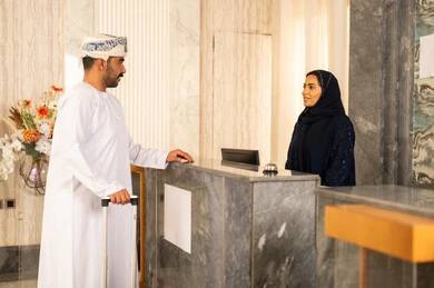 خدمة العملاء والاستقبال, رجل عربي خليجي عماني يرتدي الدشداشة و العمامة يمسك حقيبة السفر و يقوم بالاستفسار فى خدمة العملاء، حسن الاستقبال والبشاشة خدمة العملاء والاستقبال, رجل عربي خليجي عماني يرتدي الدشداشة و العمامة يمسك حقيبة السفر و يقوم بالاستفسار فى خدمة العملاء، حسن الاستقبال والبشاشة
