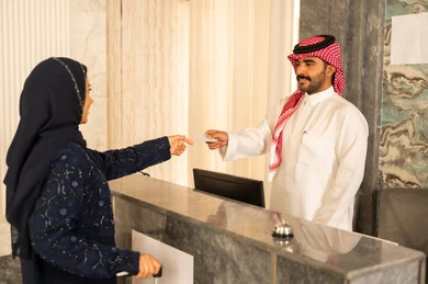 إتمام إجراءات حجز غرفة، ايماءات السرور والسعادة ، خدمة ومكتب إستقبال العملاء ، امراه عربيه خليجيه سعودية ترتدي العباءة و الحجاب تستلم بطاقة الغرفه