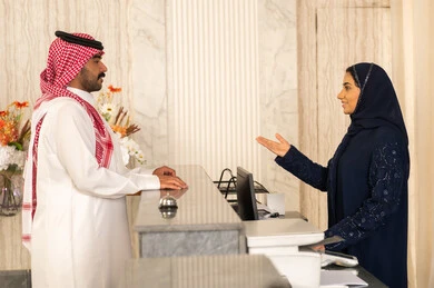 إنهاء إجراء الدخول للفندق، مفهوم السياحه والفندقه والسفر، رجل عربي خليجي سعودي يرتدي الثوب الابيض و الشماغ يقوم بالاستفسار فى خدمة العملاء