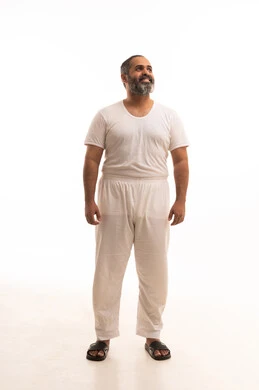 الوقوف باستقامة والنظر إلى شيء ما، مفهوم لغة الجسد، ملابس داخلية رجالية مريحة باللون الابيض، إيماءات السعادة والسرور، أزياء عربية سعودية، بورتريه لرجل عربي خليجي سعودي وسيم يرتدي سروال وفنيله بيضاء ينظر بفرح، صورة لكامل الجسم، خلفية بيضاء