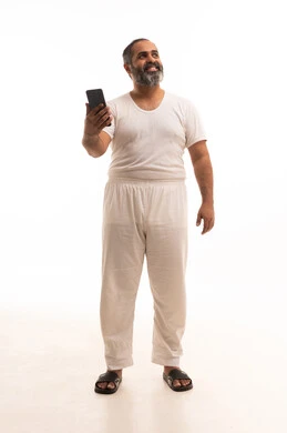 Looking at something, online shopping and browsing mobile programs and applications, chatting with family and friends, a portrait of a Saudi Arabian Gulf man wearing white pants and a shirt holding a mobile phone, the evolution of technology and technical devices, full-body image, white background.