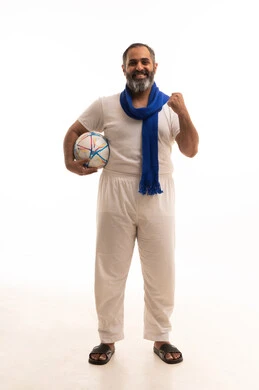 المباريات و الألعاب الرياضية, بورتريه لرجل عربي خليجي سعودي يرتدي سروال وفنيله ينظر إلى الكاميرا يضع وشاح ازرق تشجيعي لفريق كرة القدم يرفع يده للاعلى يحمل الكرة, إيماءات الفوز والانتصار والحماس, صورة الجسم بالطول الكامل, خلفية بيضاء