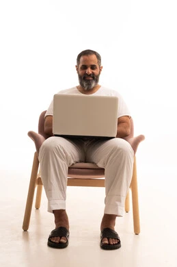 Completing work and tasks remotely via a laptop, browsing the internet and social media, a portrait of an Arab Saudi Gulf man wearing pants and a white t-shirt using a computer, white background.