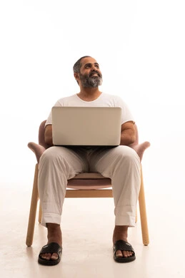 تصفح الانترنت وسائل التواصل الاجتماعي، انجاز الاعمال والمهام عن بعد عبر الحاسوب المحمول، بورتريه لرجل عربي سعودي خليجي يرتدي سروال وفانيلا أبيض يقوم باستخدام الحاسب، خلفية بيضاء