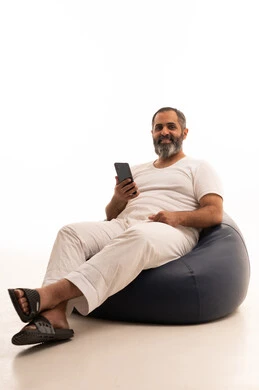 الدردشة مع الأهل والأصدقاء، التسوق الالكتروني وتصفح برامج وتطبيقات الجوال، بورتريه لرجل عربي سعودي خليجي يرتدي سروال وفانيلا أبيض يجلس على كرسي بين باج  يحمل الهاتف المحمول، تطور التكنولوجيا والأجهزة التقنية، خلفية بيضاء