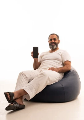 A blank black screen displayed on the mobile phone, expressions of happiness and joy, a portrait of an Arab Saudi Gulf man wearing white pants and a t-shirt sitting on a chair holding a mobile phone in his hands, white background.