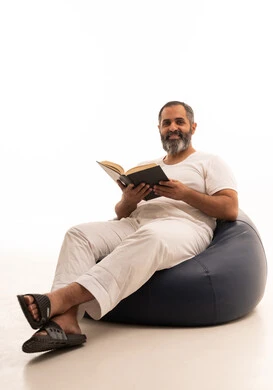 The concept of education and scientific research, spending free time learning and cultural activities, the hobby of reading and exploration, a portrait of an Arab Saudi Gulf man wearing white pants and a t-shirt sitting on a chair between bags reading a book, white background. The concept of education and scientific research, spending free time learning and cultural activities, the hobby of reading and exploration, a portrait of an Arab Saudi Gulf man wearing white pants and a t-shirt sitting on a chair between bags reading a book, white background.